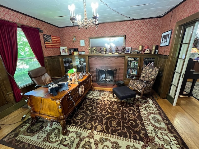 office space with crown molding, a notable chandelier, hardwood / wood-style flooring, and a fireplace