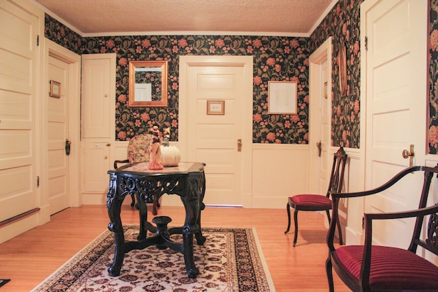 interior space featuring crown molding, light hardwood / wood-style floors, and a textured ceiling