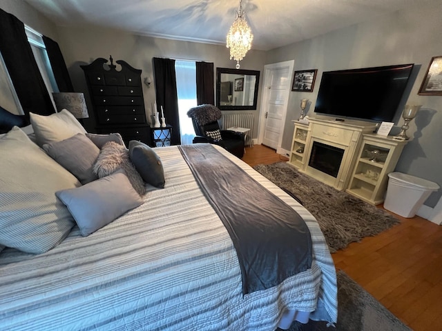 bedroom featuring hardwood / wood-style flooring, radiator heating unit, and a notable chandelier