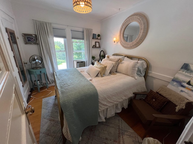 bedroom featuring a notable chandelier, wood-type flooring, and ornamental molding