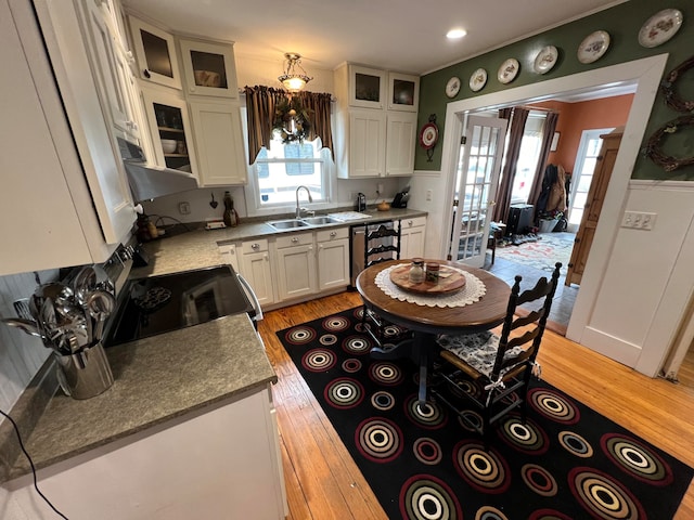 kitchen with sink, white cabinetry, light stone countertops, decorative light fixtures, and light wood-type flooring