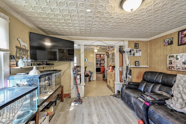 living room with ornamental molding, light wood-type flooring, and wooden walls