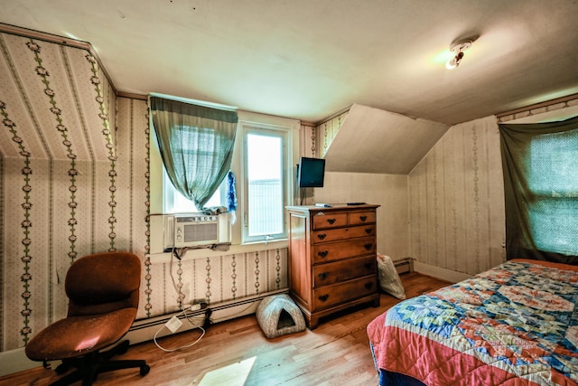 bedroom with hardwood / wood-style floors, vaulted ceiling, a baseboard heating unit, and cooling unit