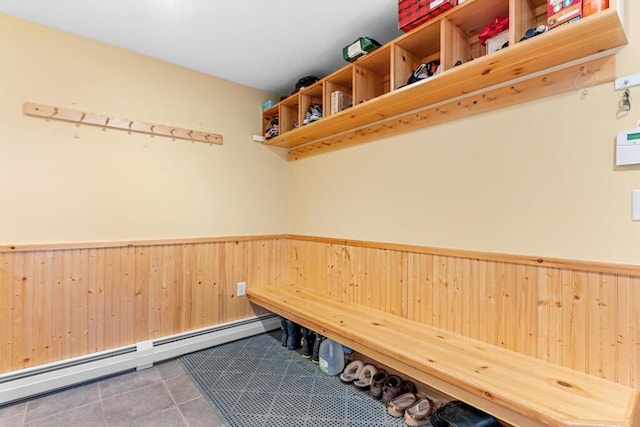 mudroom with tile patterned flooring, wooden walls, and a baseboard heating unit