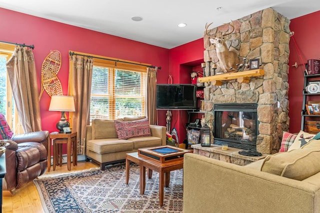 living room with hardwood / wood-style floors and a stone fireplace