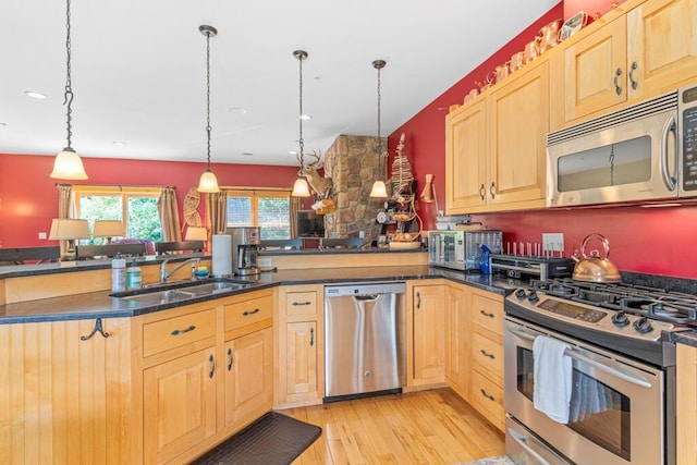 kitchen featuring pendant lighting, kitchen peninsula, sink, and appliances with stainless steel finishes