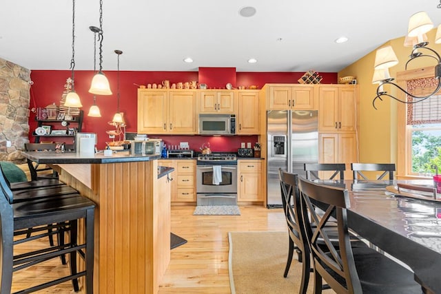 kitchen featuring pendant lighting, light brown cabinets, light wood-type flooring, and appliances with stainless steel finishes