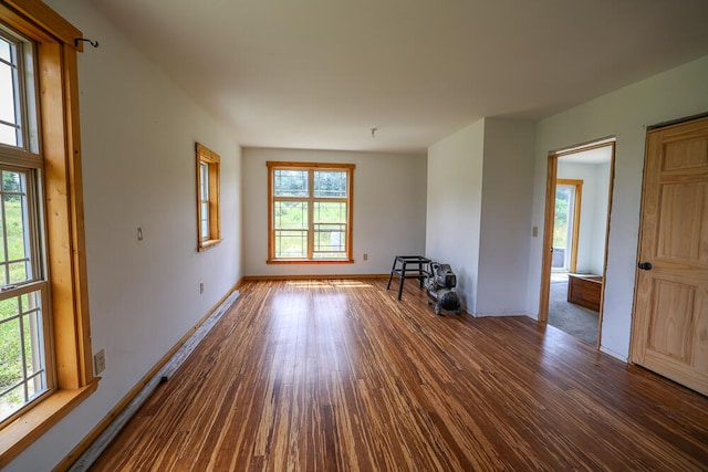 spare room with a wealth of natural light and dark wood-type flooring