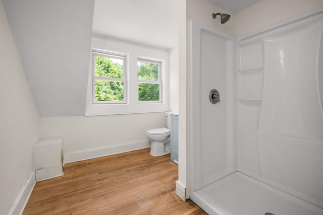 bathroom featuring vaulted ceiling, toilet, a shower, and wood-type flooring