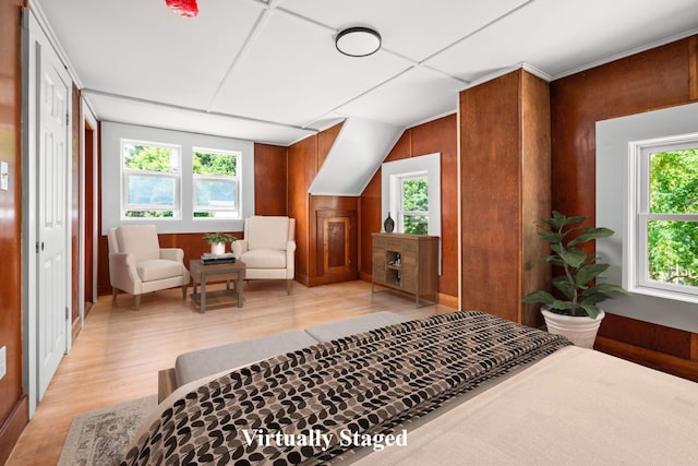 bedroom with wooden walls, multiple windows, and light hardwood / wood-style floors