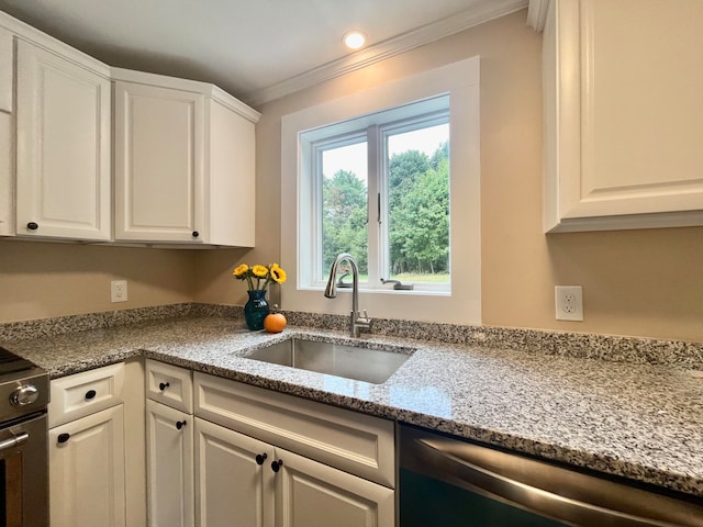 kitchen with light stone counters, white cabinets, stainless steel appliances, and sink