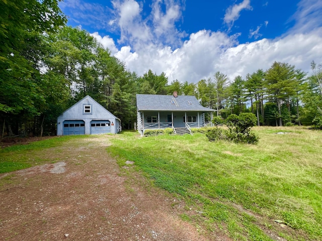 view of front of house with a front yard, covered porch, a garage, and an outbuilding