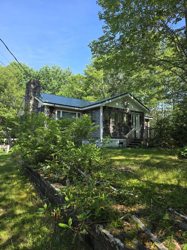 19 Resh Rd, Searsport, ME 04974 - view of property exterior featuring a metal roof, a chimney, a lawn, and a deck
