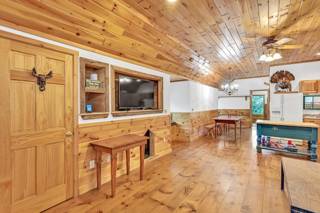 interior space featuring vaulted ceiling, ceiling fan with notable chandelier, light hardwood / wood-style flooring, wood ceiling, and wooden walls