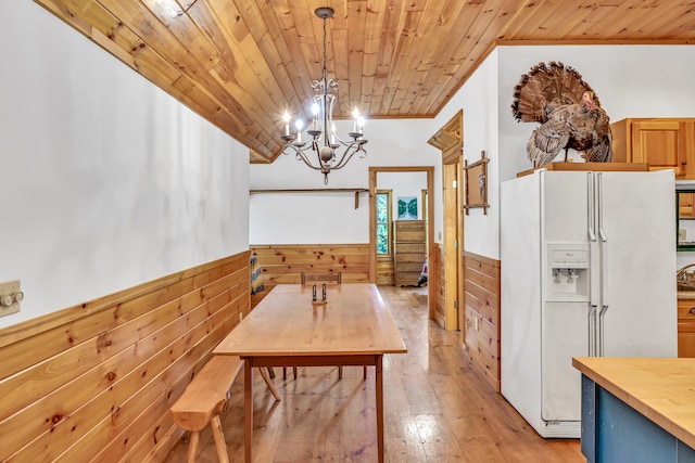 dining room with ornamental molding, light hardwood / wood-style flooring, wood walls, an inviting chandelier, and wooden ceiling