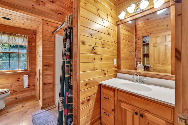 bathroom with vanity, toilet, wood-type flooring, and wooden walls