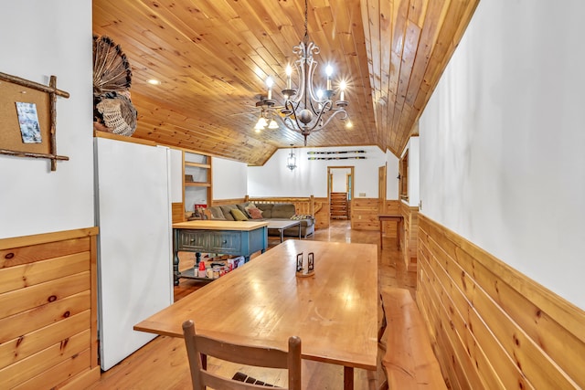 dining room with wood ceiling, a chandelier, wood walls, and light hardwood / wood-style floors