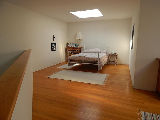 bedroom featuring a skylight and light hardwood / wood-style flooring