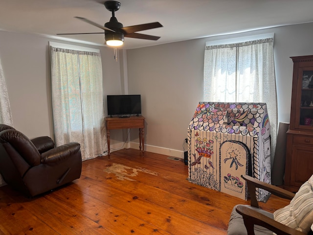 living room with wood-type flooring, ceiling fan, and a healthy amount of sunlight