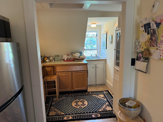 kitchen featuring light tile patterned flooring, stainless steel fridge, and sink