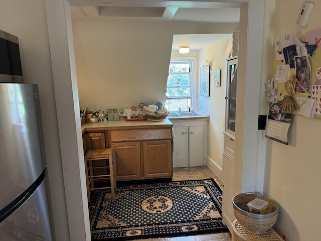 kitchen with light countertops, a sink, and freestanding refrigerator