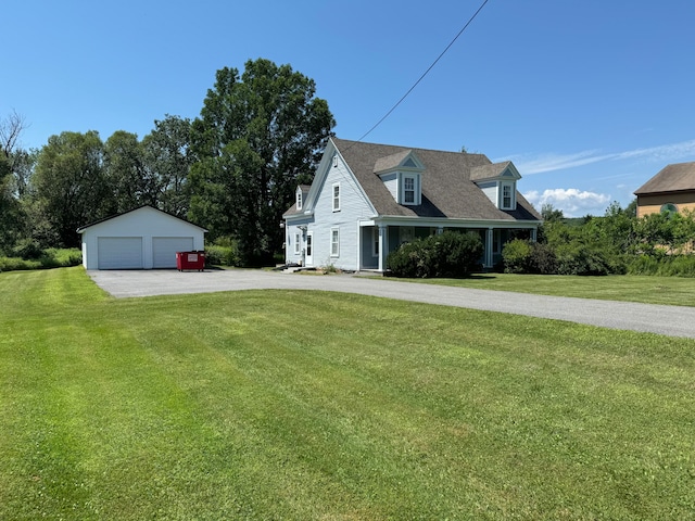 view of front of house featuring a garage, an outbuilding, and a front lawn