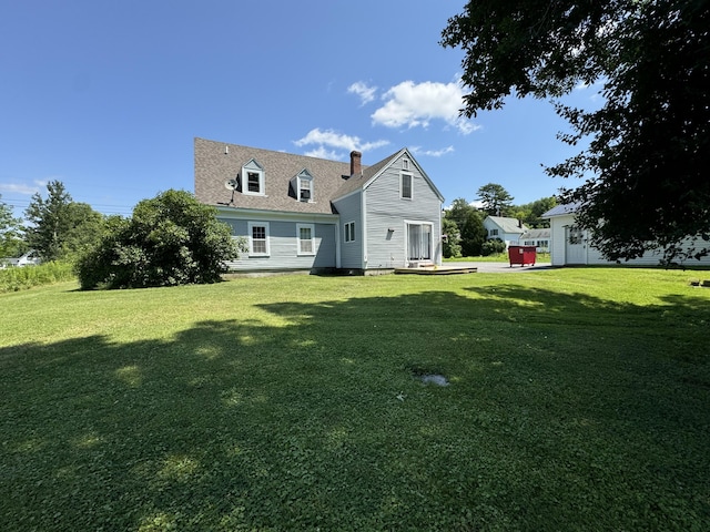 back of property with a chimney and a lawn