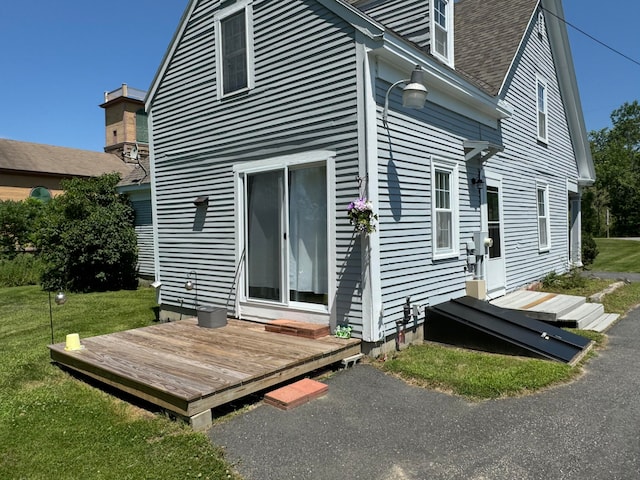 back of house with a deck and a lawn