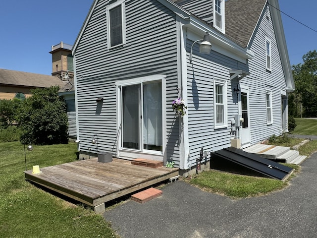 rear view of house featuring a lawn, a wooden deck, and entry steps
