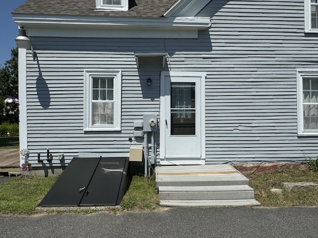 view of exterior entry with a shingled roof