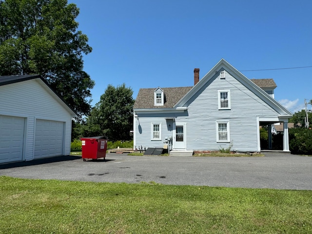 back of property with an outdoor structure, a garage, and a lawn