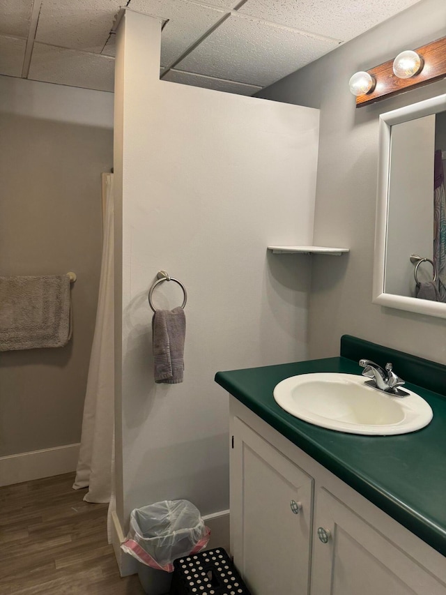 bathroom with wood-type flooring, vanity, and a paneled ceiling