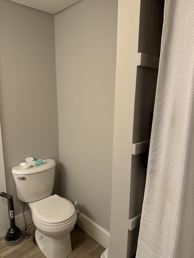 bathroom featuring toilet, baseboards, and wood finished floors
