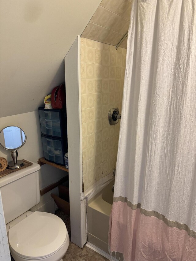 bathroom featuring toilet, shower / bathtub combination with curtain, and vaulted ceiling