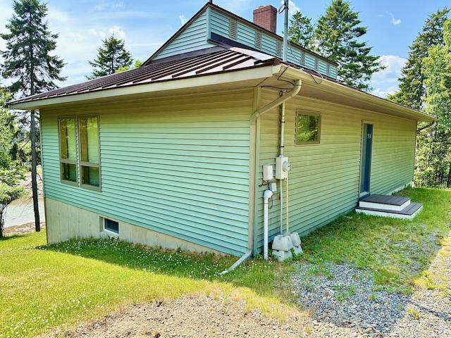 54 Harbor Hills Ln, Addison, ME 04606 - view of home's exterior featuring a chimney, metal roof, a yard, and a standing seam roof