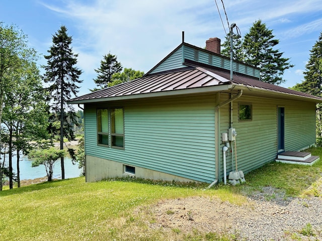 54 Harbor Hills Ln, Addison, ME 04606 - view of side of property with a chimney, a standing seam roof, metal roof, a yard, and a water view