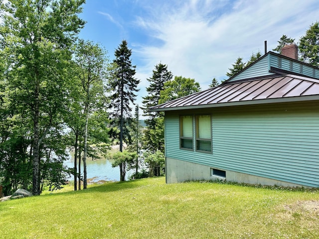 54 Harbor Hills Ln, Addison, ME 04606 - view of property exterior featuring a standing seam roof, a chimney, a yard, metal roof, and a water view