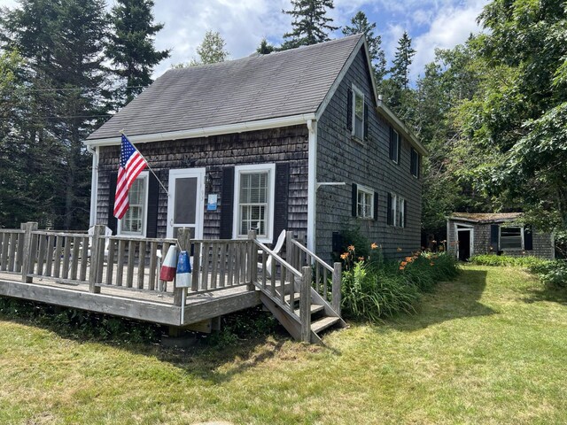 exterior space featuring a wooden deck, an outdoor structure, and a front yard