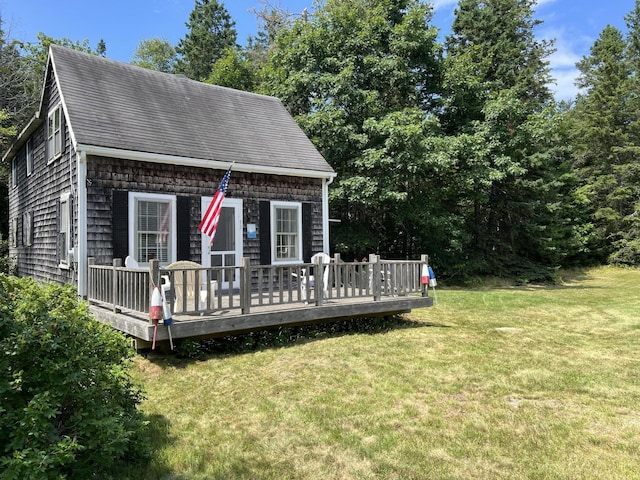 view of front of home with a shingled roof, a wooden deck, and a front lawn