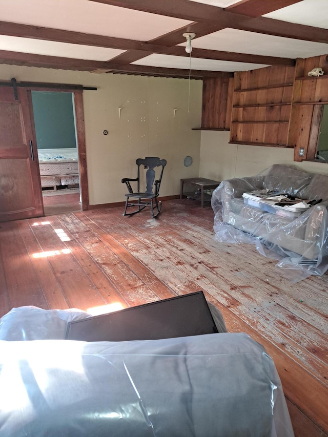 interior space with beam ceiling, hardwood / wood-style flooring, and a barn door