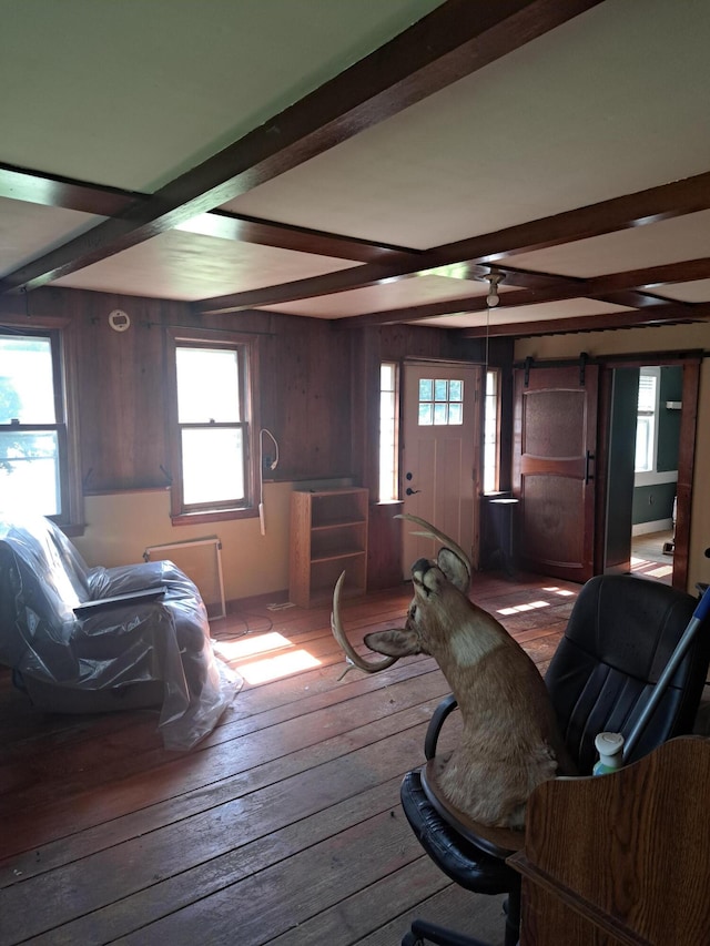 living room featuring beam ceiling, wood walls, and wood-type flooring