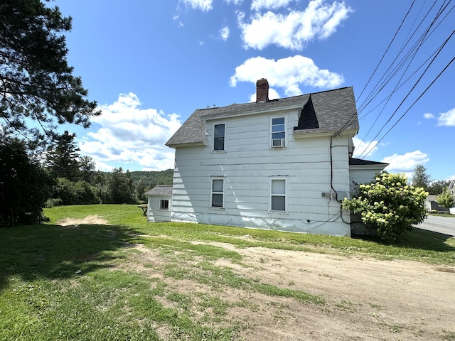 rear view of house with cooling unit, a chimney, roof with shingles, and a yard