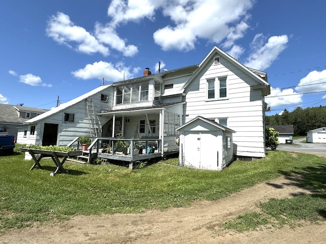 rear view of property with a lawn, covered porch, and a storage shed