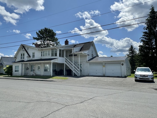 view of front of house with driveway, a chimney, and a garage