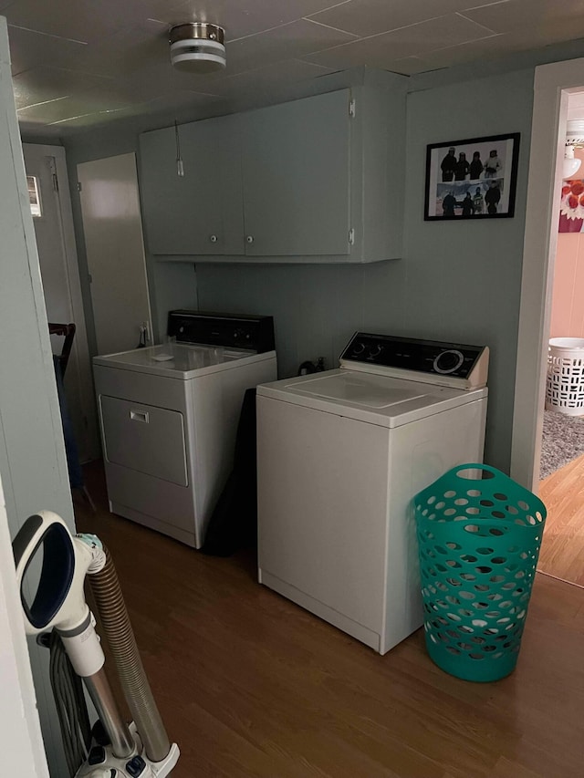 clothes washing area featuring hardwood / wood-style floors, cabinets, and independent washer and dryer