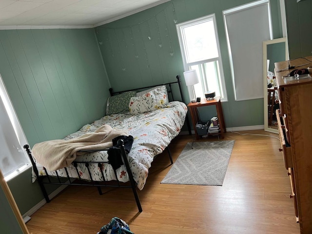 bedroom with wood finished floors and crown molding
