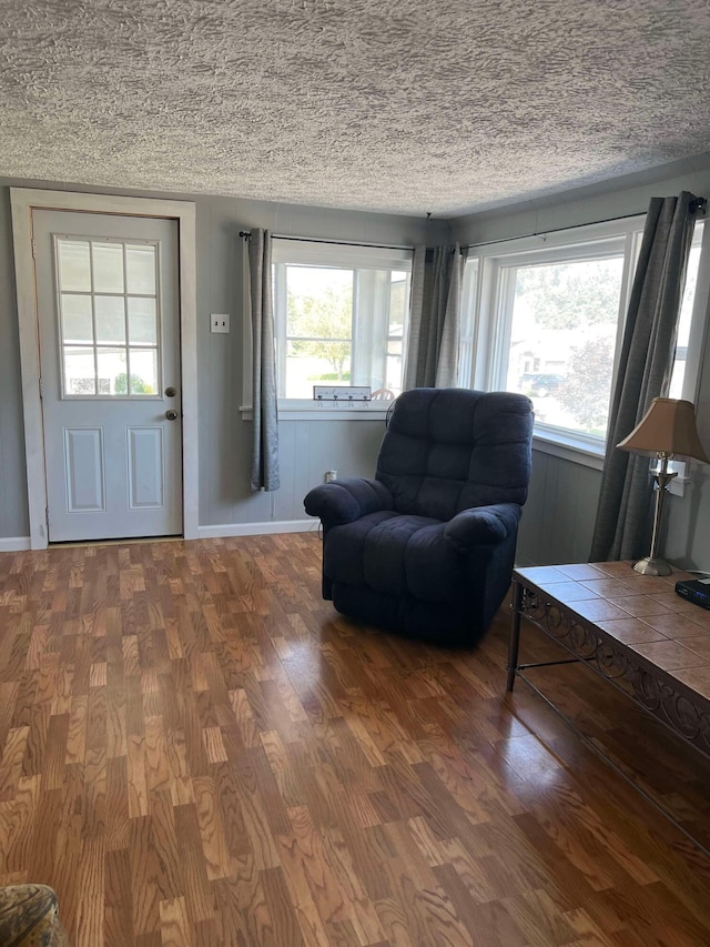 interior space with baseboards, a textured ceiling, and wood finished floors