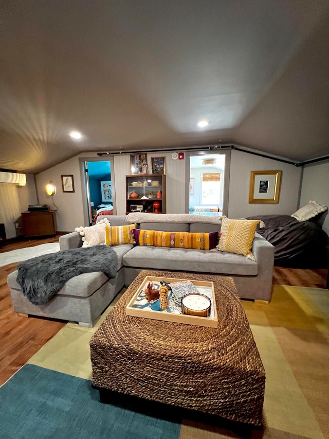 living room featuring a wall unit AC, lofted ceiling, and hardwood / wood-style flooring