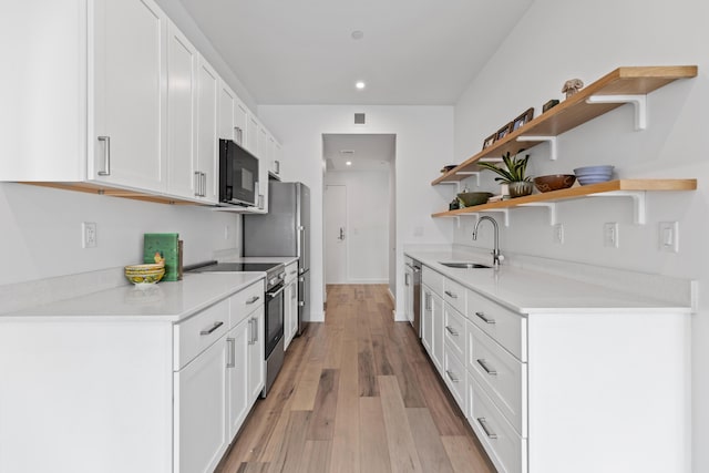 kitchen with white cabinetry, sink, stainless steel appliances, and light hardwood / wood-style floors