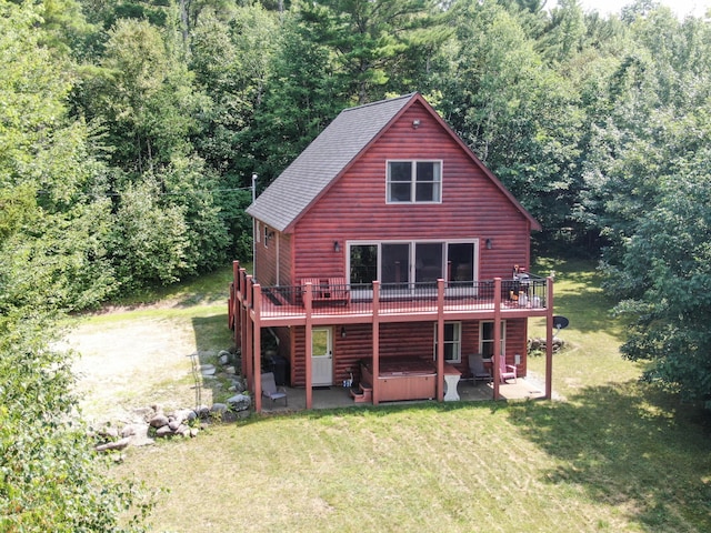 back of house featuring a hot tub, faux log siding, a lawn, a wooden deck, and a patio area